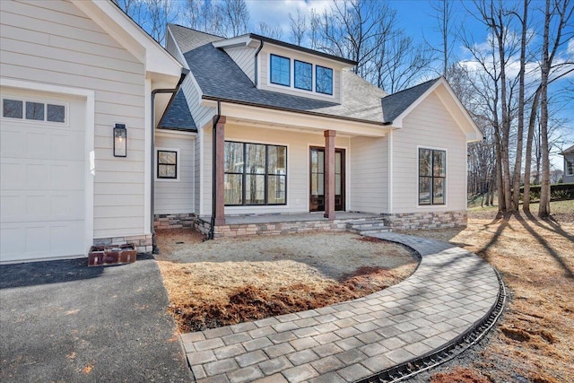 view of front of property with a shingled roof, covered porch, and an attached garage