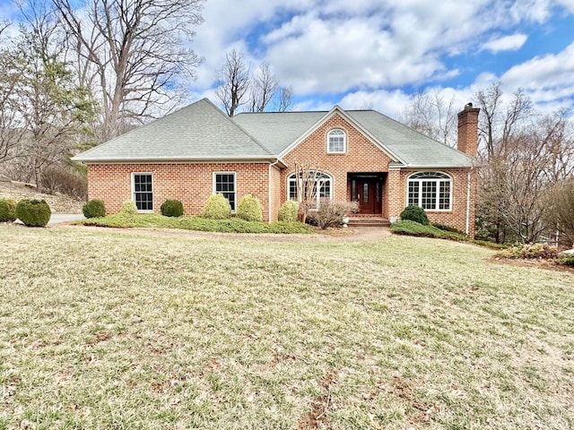 view of front of property featuring a front yard, brick siding, a chimney, and roof with shingles