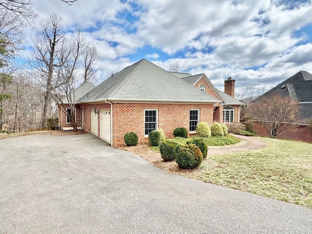 view of home's exterior with driveway, a shingled roof, a chimney, an attached garage, and brick siding