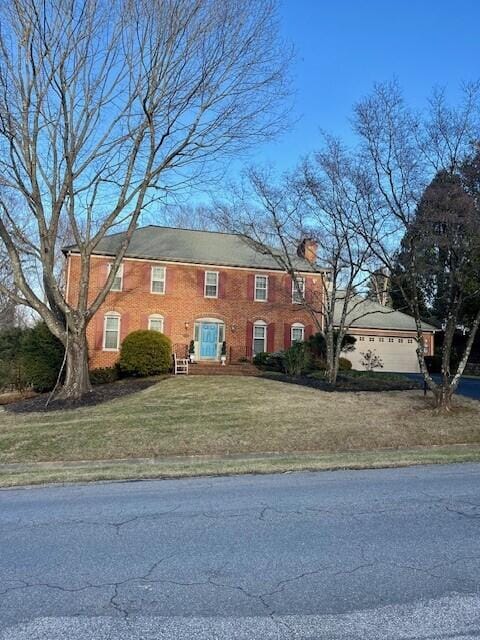 view of front of house featuring a chimney, a front lawn, and brick siding