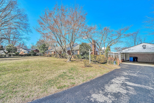 ranch-style house featuring brick siding, a front yard, a carport, a residential view, and driveway