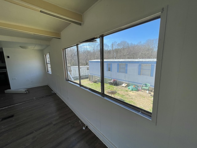 interior space featuring dark wood-type flooring, a wealth of natural light, beamed ceiling, and baseboards