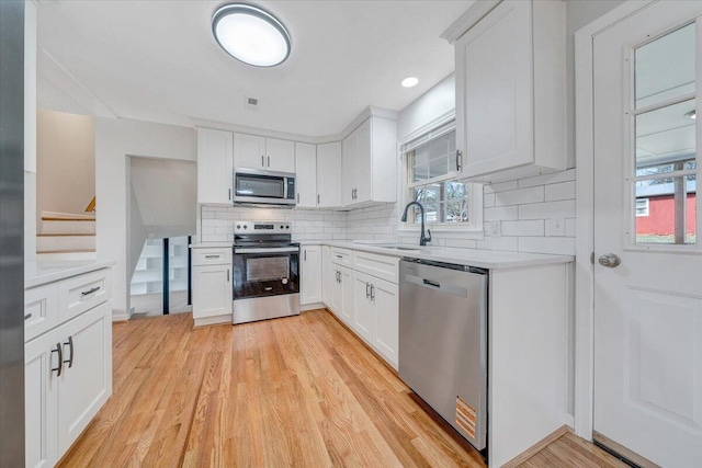 kitchen with stainless steel appliances, light countertops, a sink, and tasteful backsplash