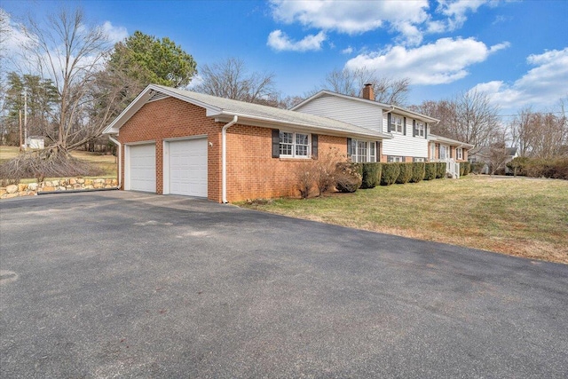 view of property exterior with an attached garage, brick siding, a yard, driveway, and a chimney