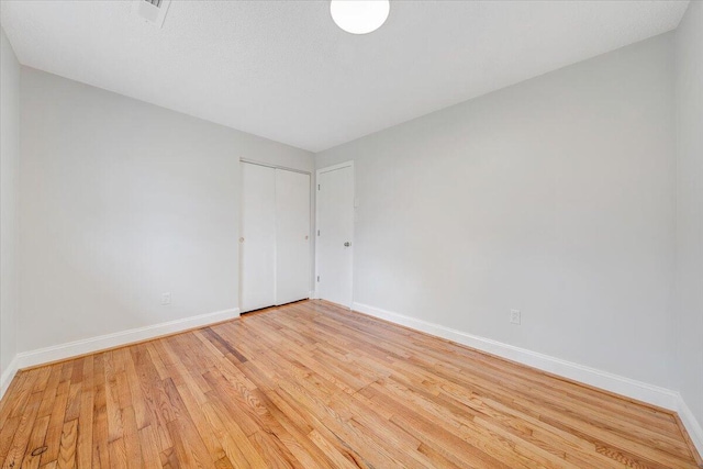 unfurnished room with light wood-type flooring and baseboards