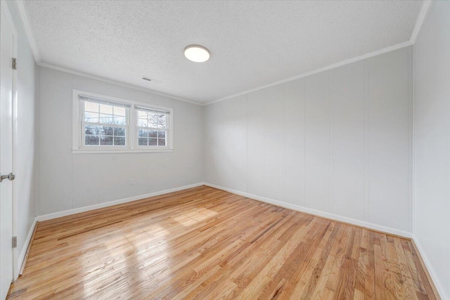 unfurnished room with crown molding, a textured ceiling, visible vents, and wood finished floors