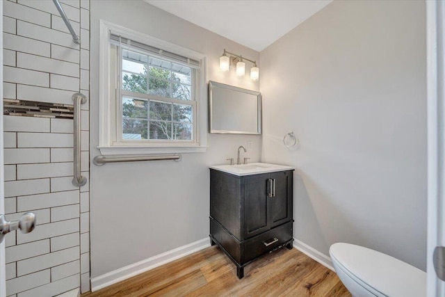 bathroom with toilet, vanity, baseboards, and wood finished floors