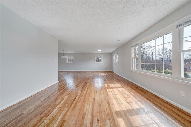 spare room featuring a textured ceiling, light wood-style flooring, and baseboards