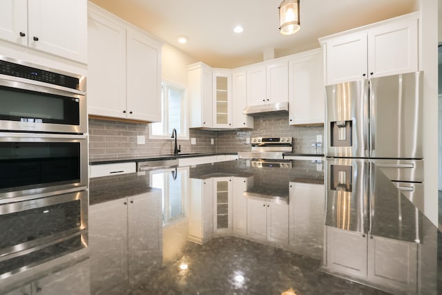 kitchen with under cabinet range hood, stainless steel appliances, a sink, white cabinetry, and tasteful backsplash