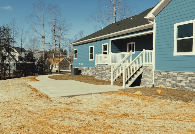 back of property featuring stairs, a shingled roof, and cooling unit