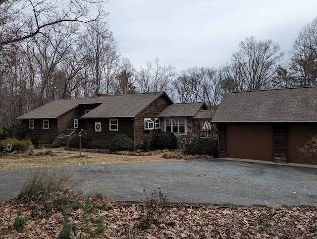 view of front facade featuring driveway, roof with shingles, and an attached garage