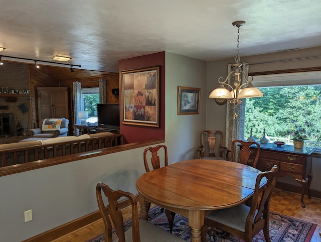 dining area with a fireplace, rail lighting, and a notable chandelier