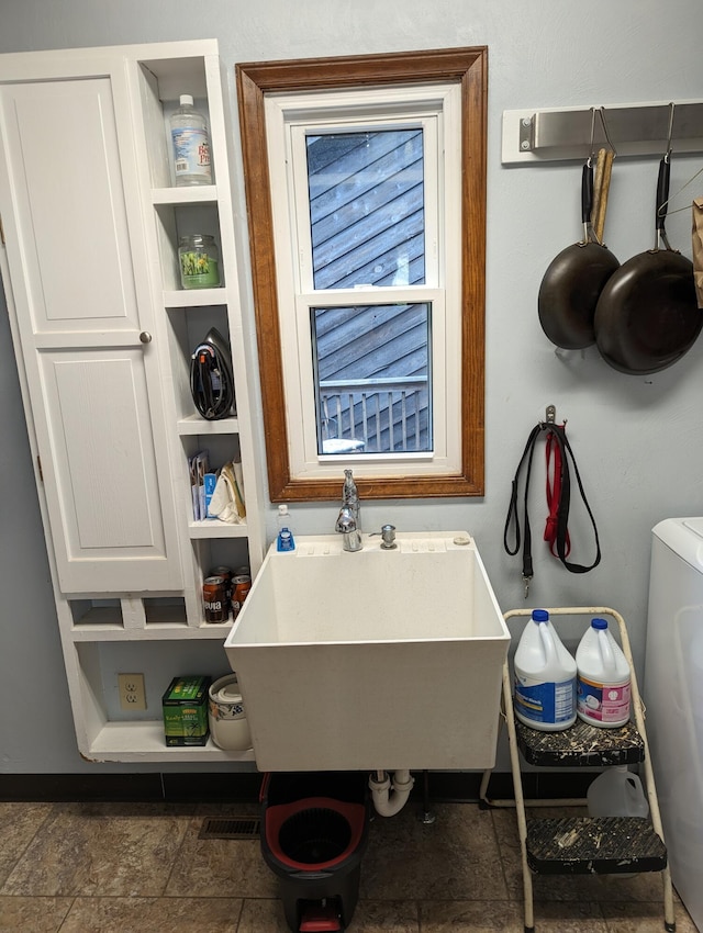 bathroom with washer / clothes dryer, a freestanding tub, and a sink