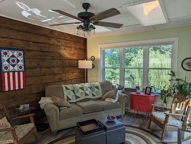 living area featuring ceiling fan, a skylight, and wood finished floors