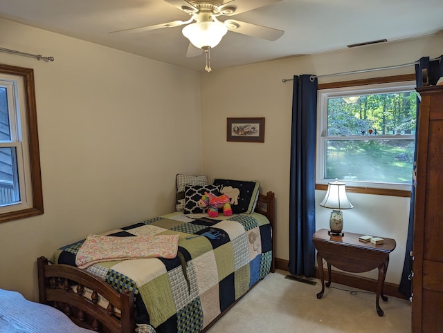 bedroom with light carpet, visible vents, and a ceiling fan