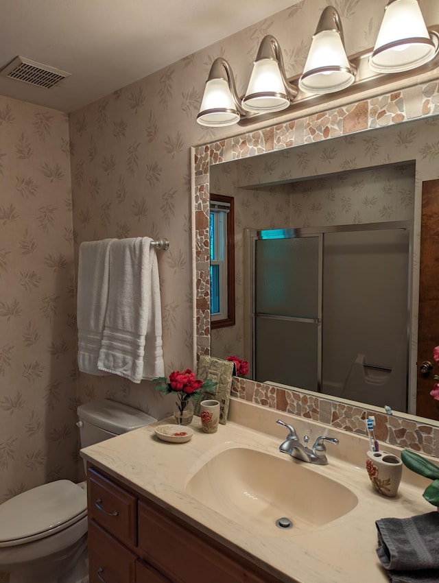 bathroom with visible vents, vanity, toilet, and wallpapered walls