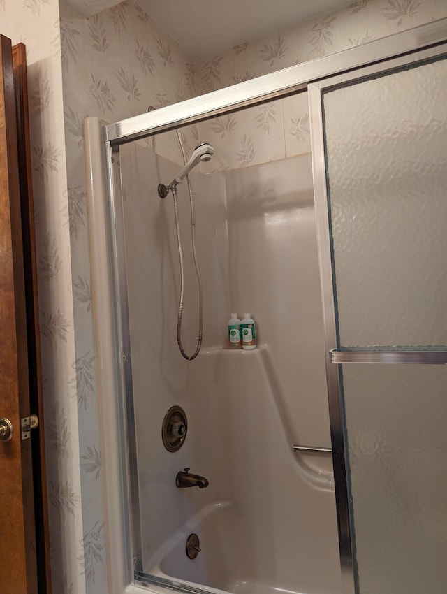 full bath featuring wallpapered walls and shower / bath combination with glass door