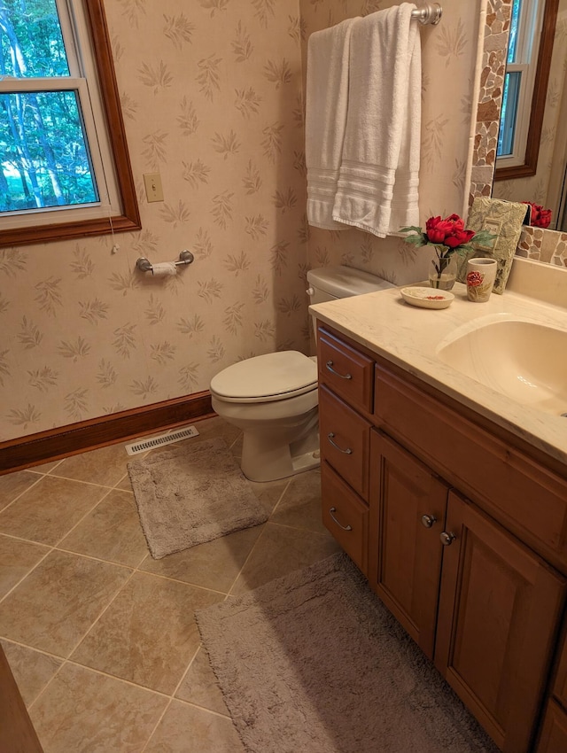 bathroom with vanity, baseboards, visible vents, tile patterned floors, and wallpapered walls