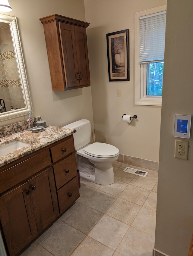 bathroom with baseboards, visible vents, toilet, tile patterned floors, and vanity