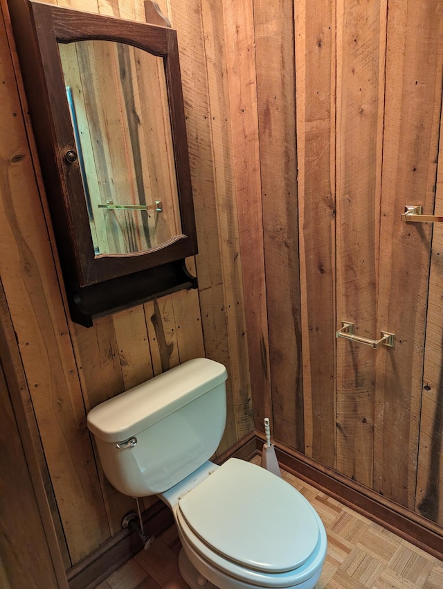 bathroom featuring wooden walls and toilet