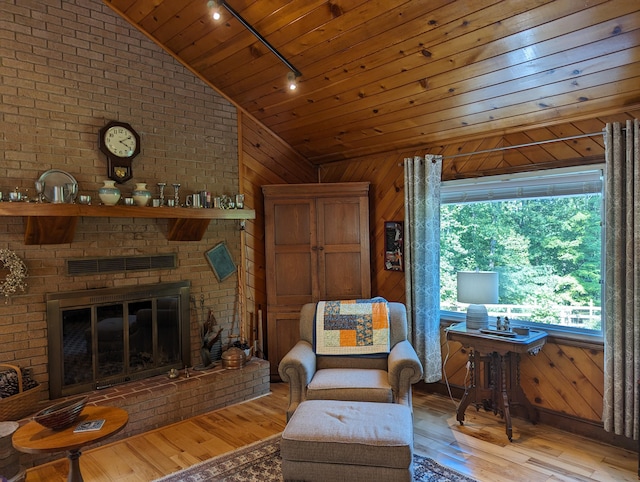 living area with visible vents, wood ceiling, vaulted ceiling, light wood-type flooring, and wood walls