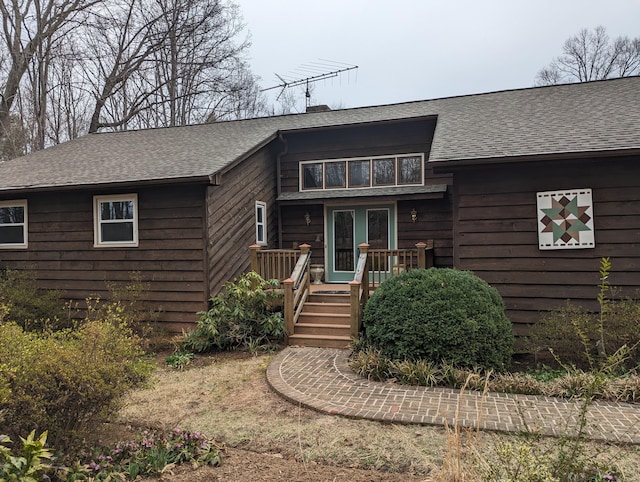 view of front of property featuring a deck and roof with shingles