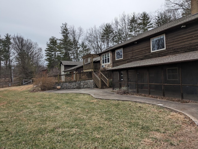 back of property with a deck, a yard, and roof with shingles