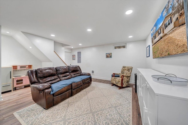 living area with recessed lighting, electric panel, light wood-style flooring, and baseboards