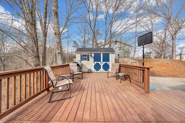 wooden deck featuring fence, a storage unit, and an outbuilding