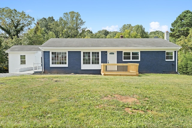 ranch-style home featuring a chimney, brick siding, a deck, and a front lawn