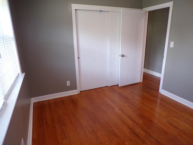 unfurnished bedroom with a closet, wood finished floors, and baseboards