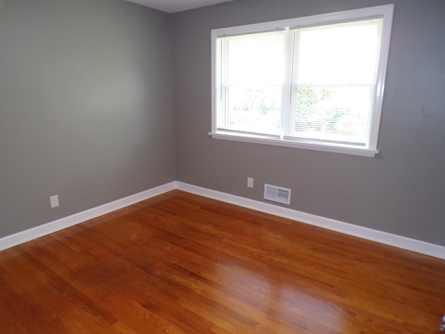 empty room featuring visible vents, baseboards, and wood finished floors