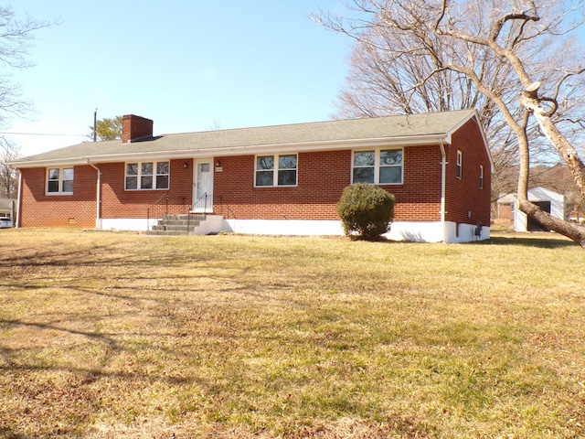 ranch-style house featuring entry steps, brick siding, a chimney, and a front lawn