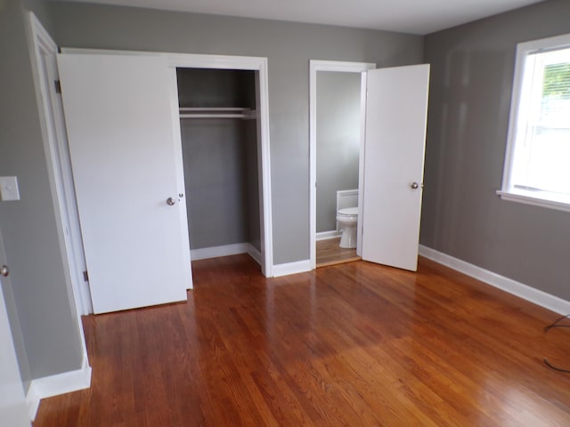 unfurnished bedroom with a closet, wood finished floors, and baseboards