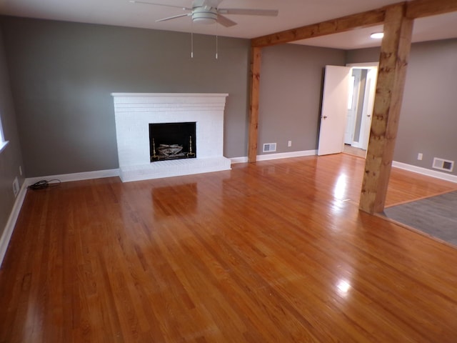 unfurnished living room featuring a fireplace, visible vents, and wood finished floors