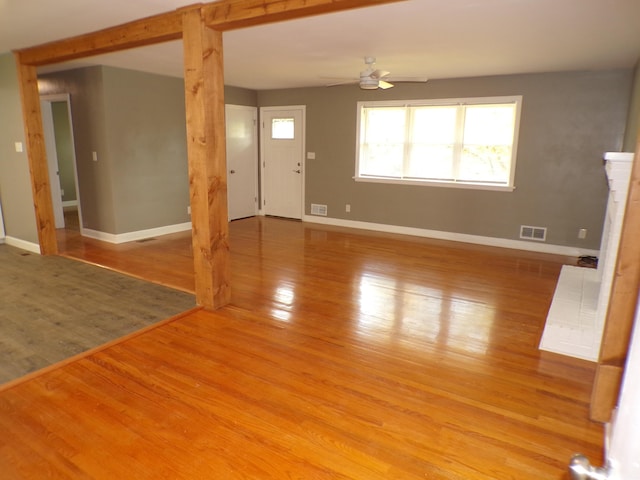 unfurnished living room with baseboards, ceiling fan, visible vents, and wood finished floors