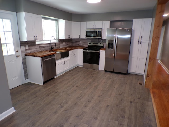 kitchen featuring dark wood-style floors, stainless steel appliances, tasteful backsplash, wooden counters, and a sink