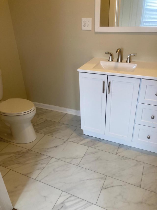 bathroom with toilet, marble finish floor, baseboards, and vanity