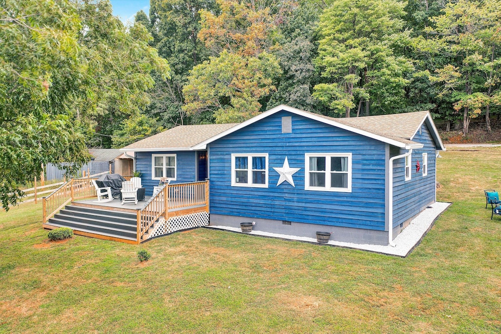 view of front facade with crawl space, roof with shingles, a front lawn, and a wooden deck