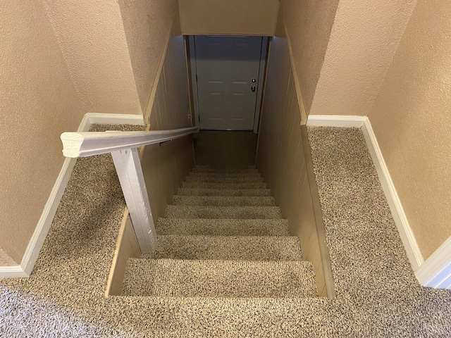 staircase featuring a textured wall and baseboards