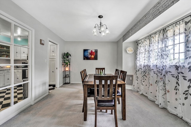 dining room with light colored carpet, a notable chandelier, and baseboards