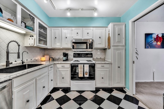 kitchen featuring stainless steel appliances, dark floors, white cabinetry, and a sink