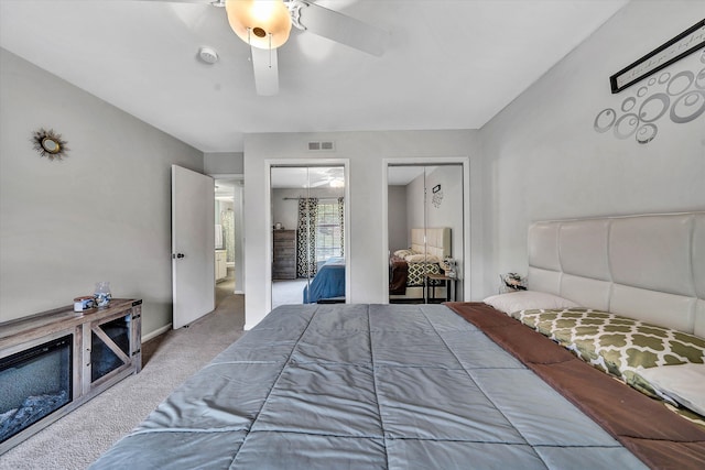 bedroom featuring a ceiling fan, baseboards, visible vents, multiple closets, and carpet