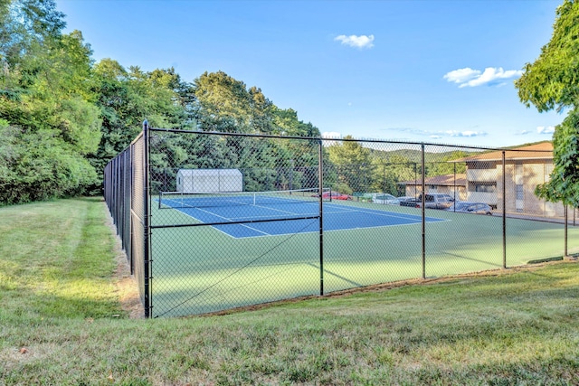 view of tennis court featuring fence and a lawn