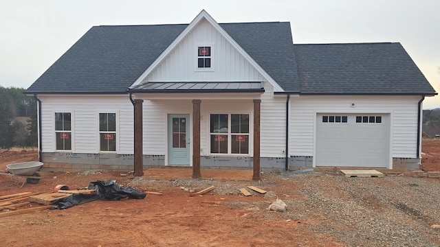 view of front facade featuring metal roof, an attached garage, driveway, roof with shingles, and a standing seam roof