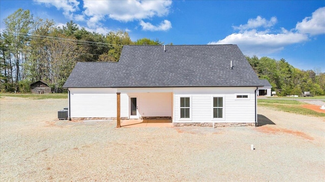 rear view of house with a shingled roof, central AC unit, and a patio area