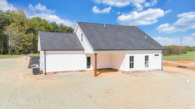 view of side of home featuring a patio area, a shingled roof, and central air condition unit