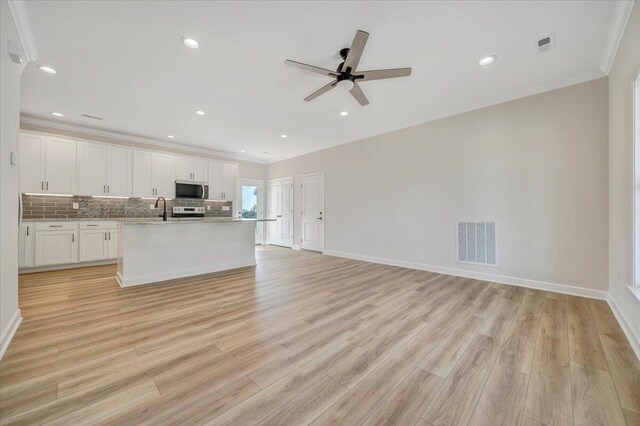 kitchen with ornamental molding, a ceiling fan, visible vents, stainless steel appliances, and a sink