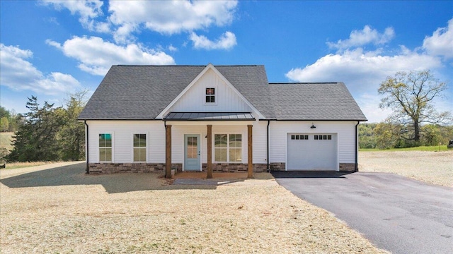 modern farmhouse with board and batten siding, aphalt driveway, a garage, a standing seam roof, and metal roof