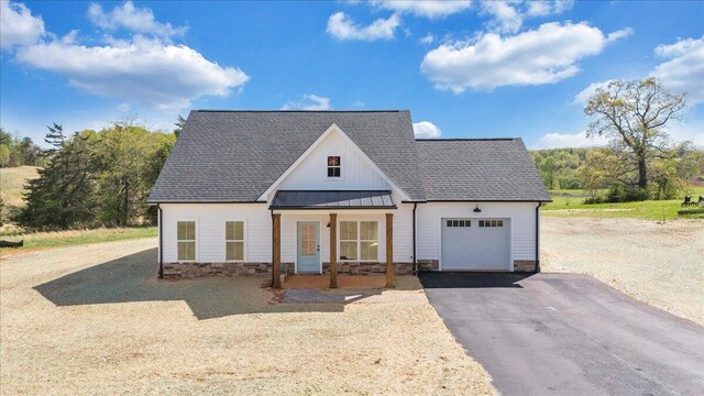 modern inspired farmhouse featuring a standing seam roof, a garage, metal roof, a shingled roof, and driveway